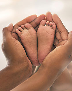 BABY FEET ENCIRCLED IN MOM HANDS