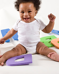 BABY SITTING ON MAT AND LAUGHING